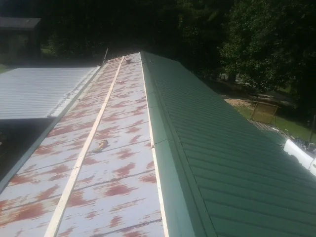 Old rusted panels beside newly installed green metal roofing — Wind Damage Roof Repair by Roofing Brothers in Baker City
