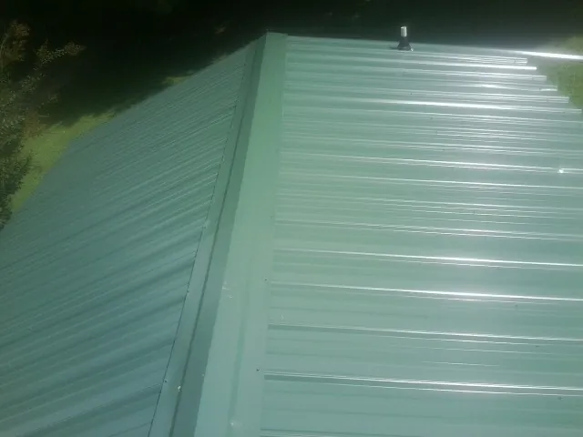 New green metal panels meeting at the ridge of a roof — Flat Roof Repair work by our crew in Baker City