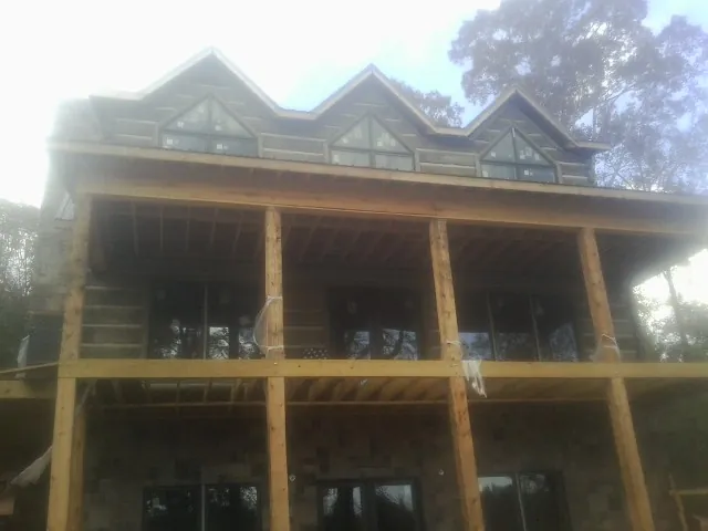 Dormers and porch framing on a large log home under construction — Roof Coating work by our crew in Baker City