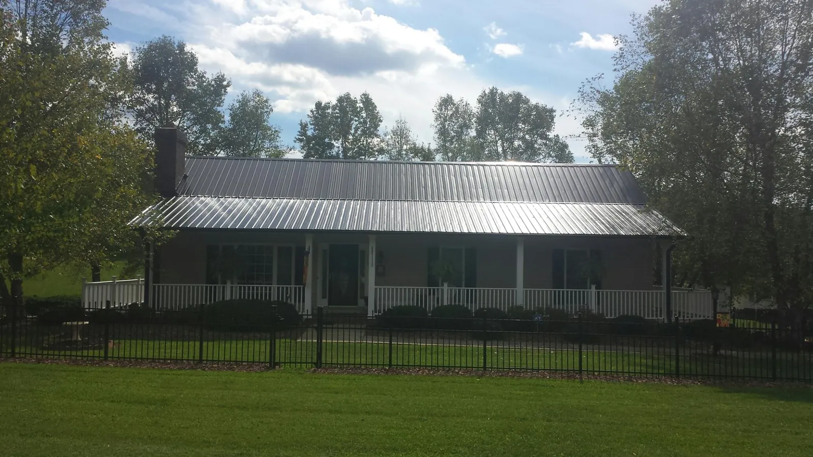 Gray metal roof on a brick ranch with a full width front porch — Gutter Guard Installation work by our crew in Baker City