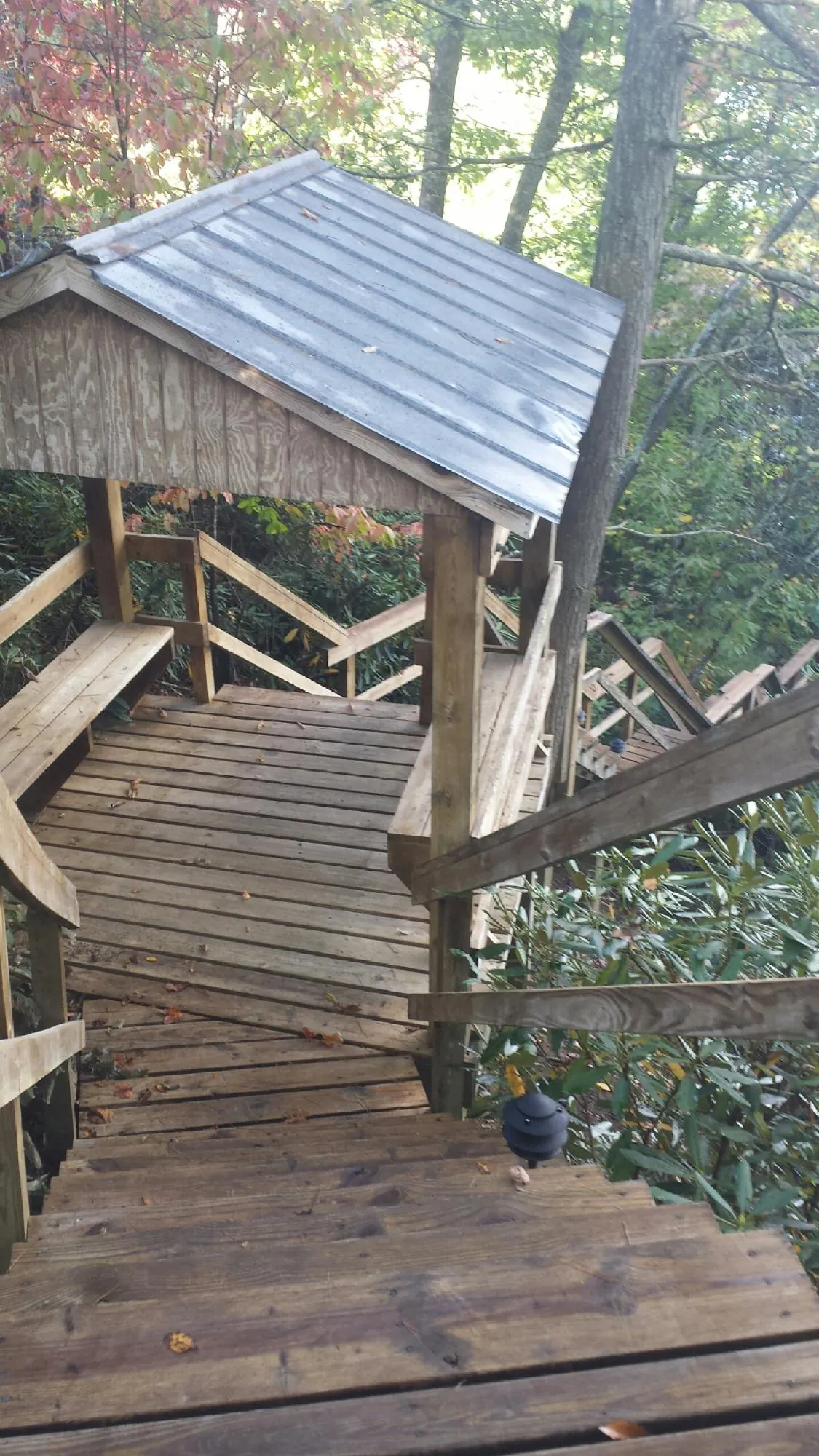 Metal roofed shelter over wooden steps on a wooded walkway — Skylight Repair & Installation work by our crew in Baker City