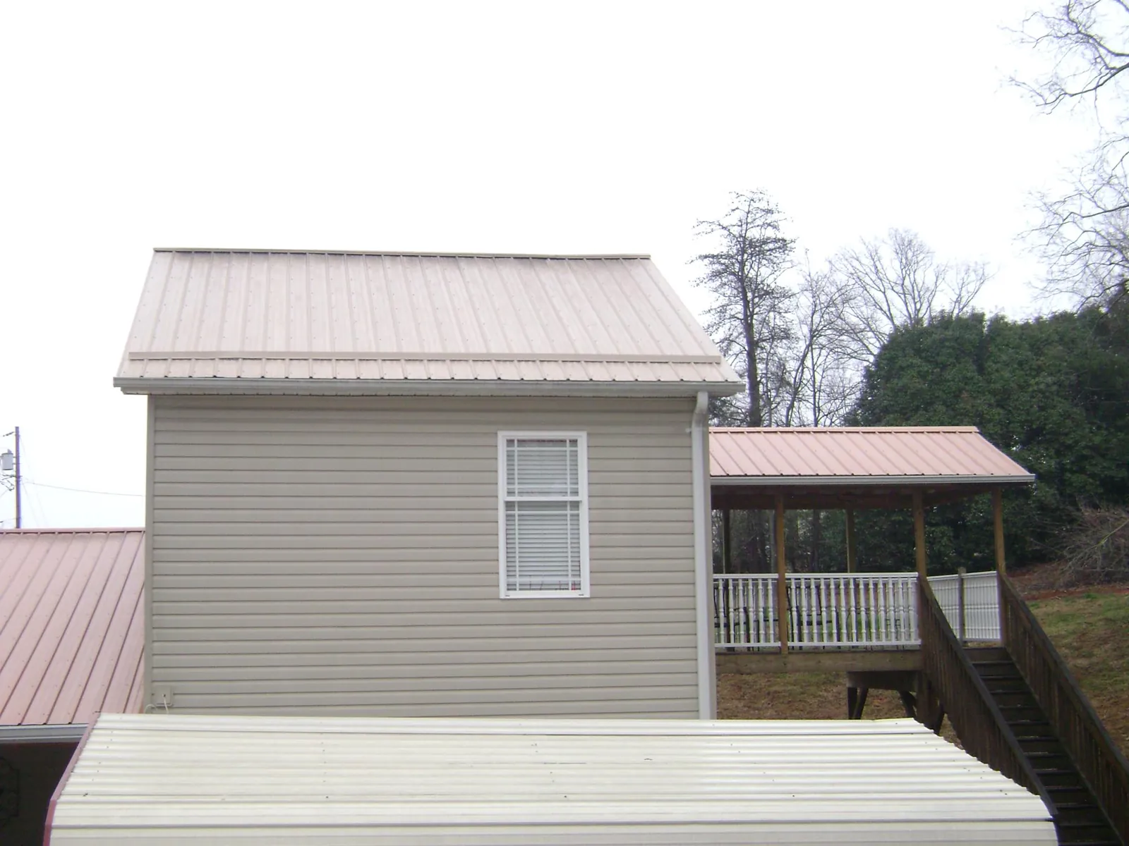 Tan metal roofs on a two story addition and attached porch, from a Roof Replacement job in Baker City